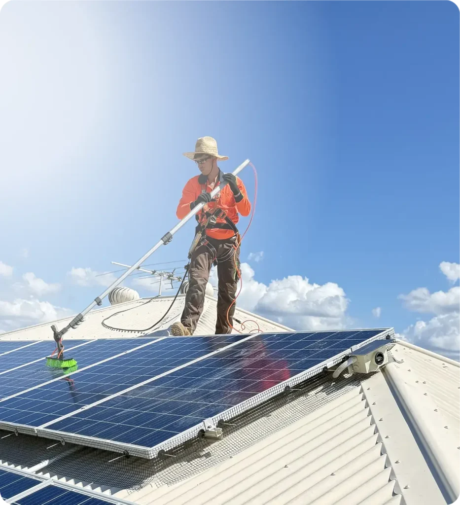 Technician cleaning solar panels with bird proofing mesh installed on a residential roof