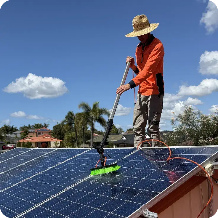 Technician cleaning residential solar panels with a water-fed brush and purified water